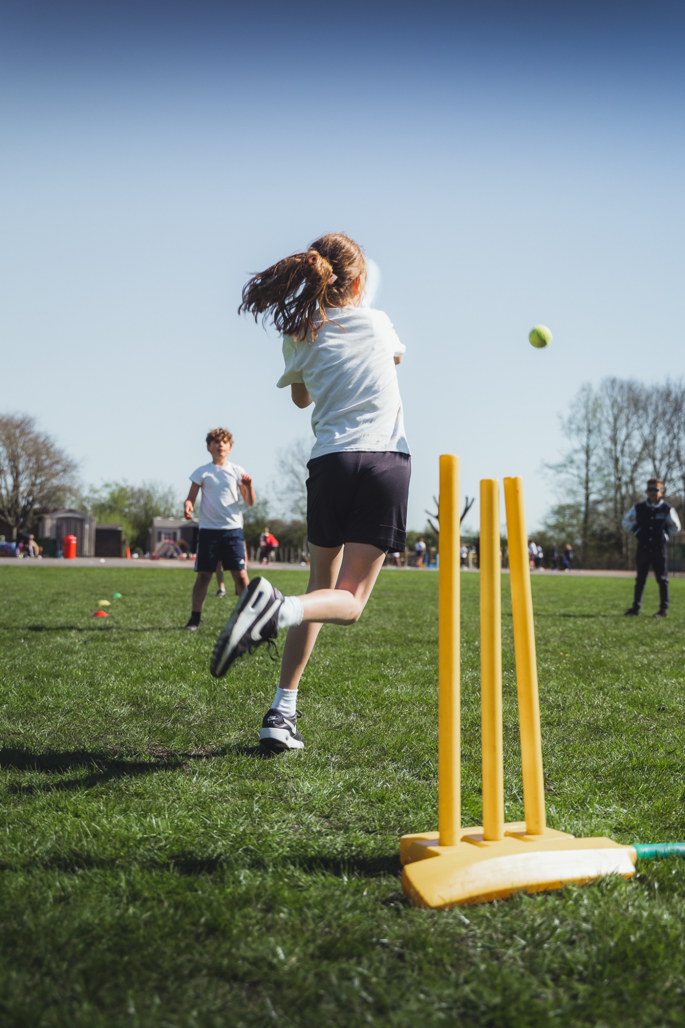 students playing cricket on school field