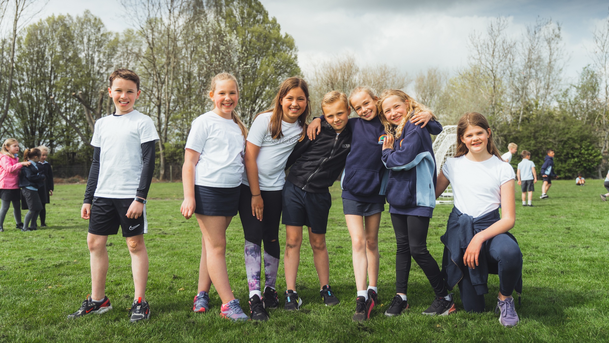 grouop of students smiling at the camera on the school field