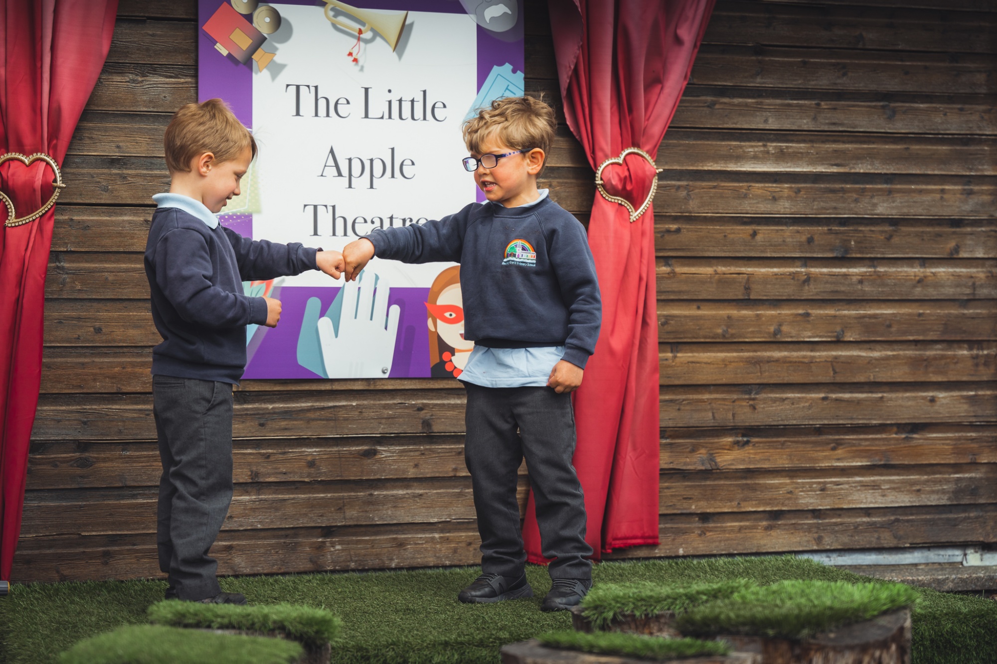 two students acting a drama performance on the outdoor stage at school
