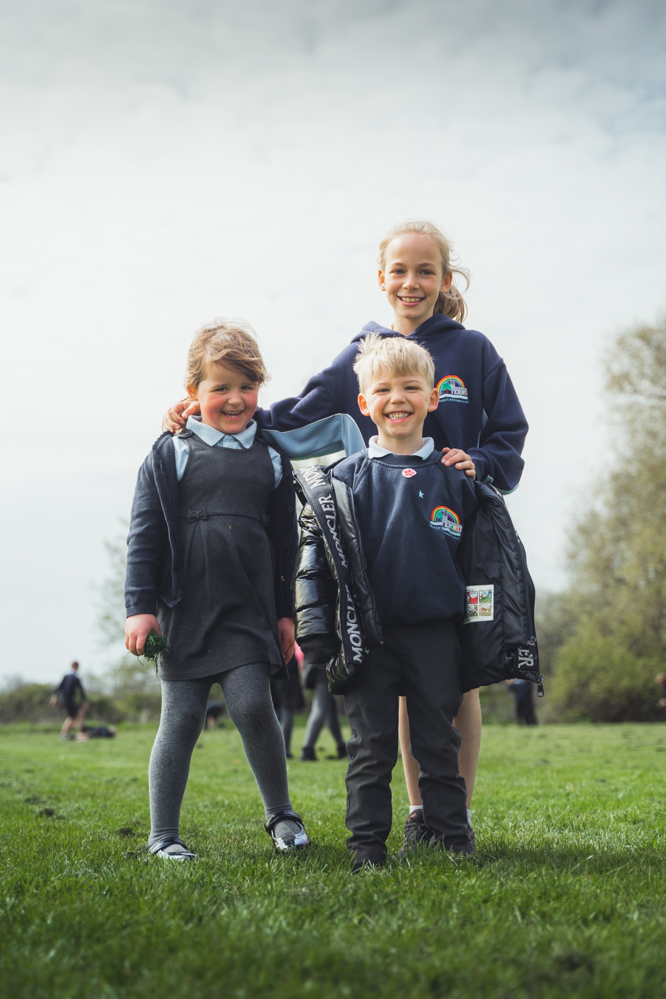 three students smiling on school field at break time