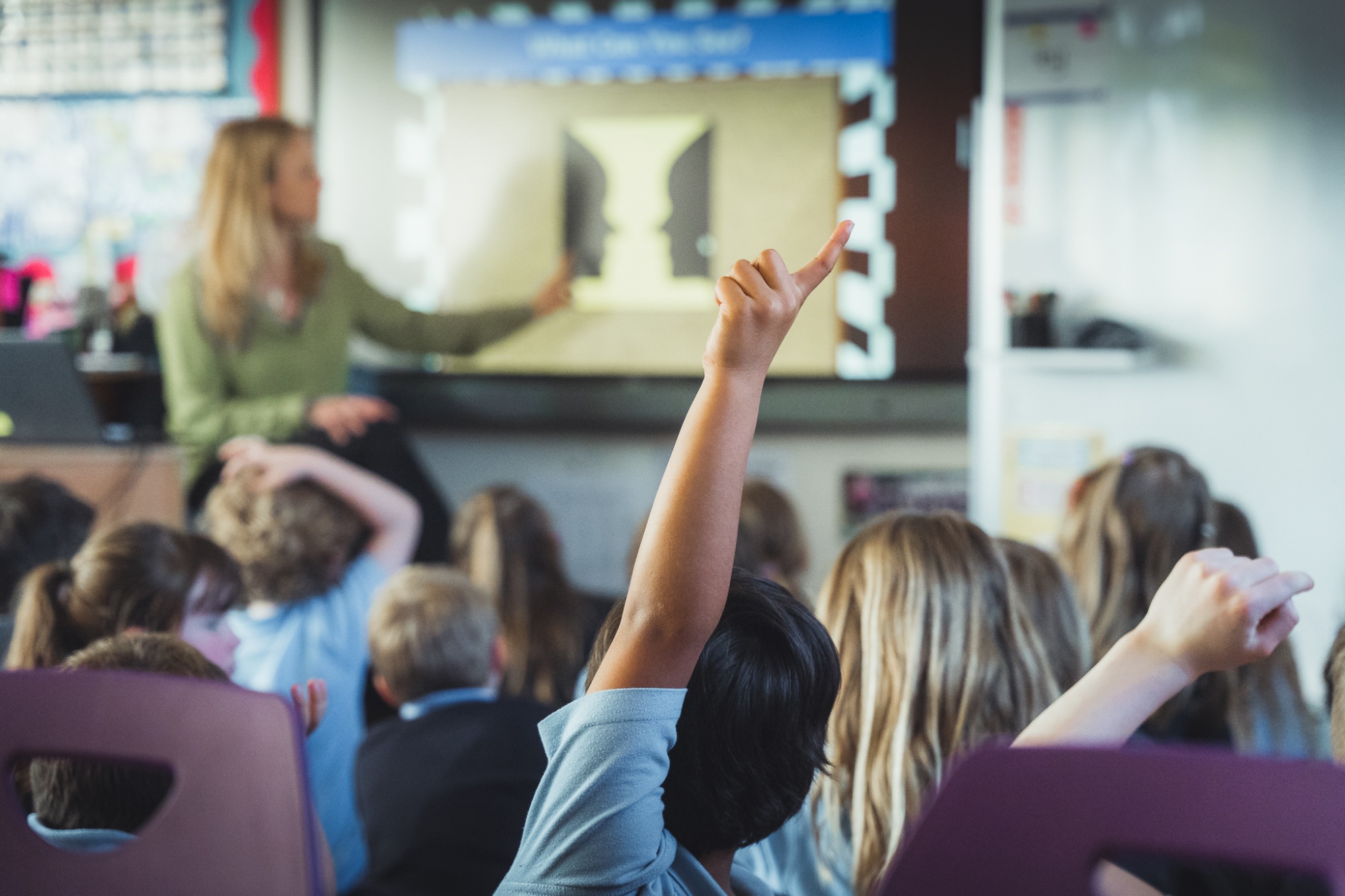student with hand up in classroom